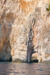 Tourists bask in the warm Mediterranean sun as they discover the stunning rocky cliffs of Zakynthos, surrounded by crystal-clear turquoise waters on a summer afternoon