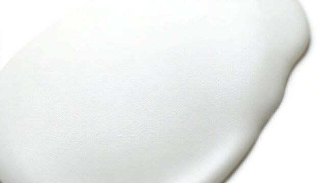 Smooth white substance being poured onto a flat surface with a clean background