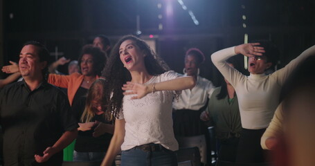 Men and women raising hands in uplifting worship session, joyful community gathering with ethnic...
