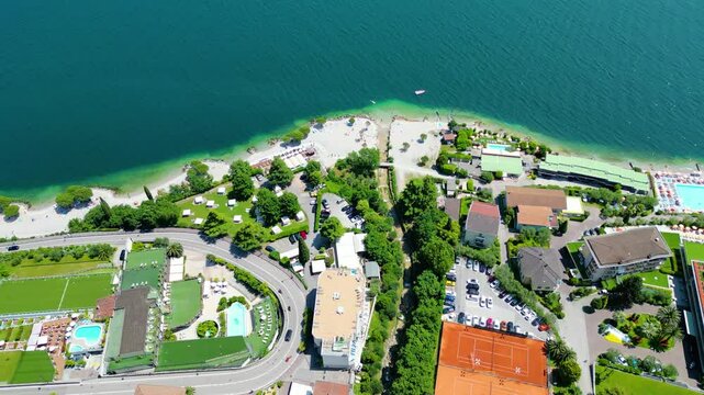 Aerial view of Limone sul Garda, a charming lakeside town with colorful houses, lush lemon terraces, bike paths along Lake Garda, and majestic mountains surrounding the crystal-clear water