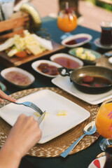 A detailed close-up of a brunette woman carefully cutting into a fluffy omelet during breakfast