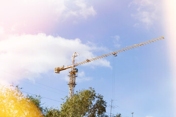 Construction crane towers over house under construction against blue sky..