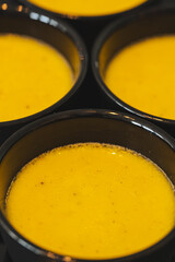 Black cups filled with creme brulee with selective focus on the first cup