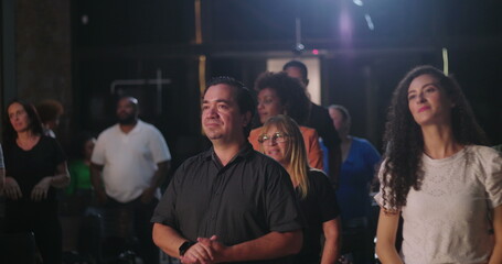 Diverse group of people standing and clapping hands in a spiritual gathering, joyful celebration of...