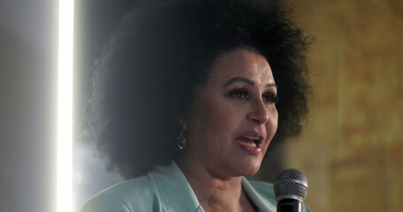Close-up of a woman speaking passionately into a microphone during a spiritual event, confident...