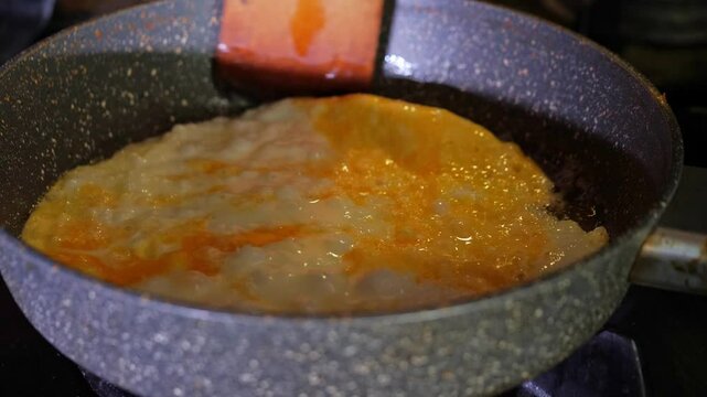 A close-up shot captures the satisfying mood of an egg actively cooking and sizzling in a frying pan with hot oil, showcasing the texture and vibrant colors of the process