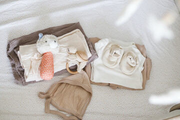 Pregnancy and getting ready for baby. Stylish baby clothes, toy, comforter in modern baby crib, top view. Preparation and making nursery