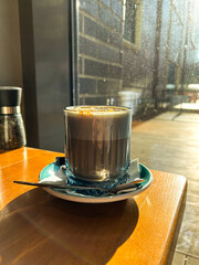 Closeup image of served cup of hot latte coffee with sweet topping on vintage wooden table in cafe. Vertical image.