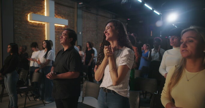 Congregation members with joyful expressions, standing during a Christian church event, reflecting spiritually with a glowing cross in the background