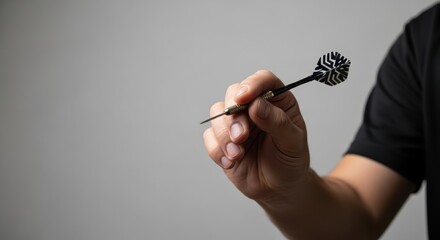 A man holding a dart preparing to throw for a game. Focus on accuracy and precision for target success. Suitable for sport concept.