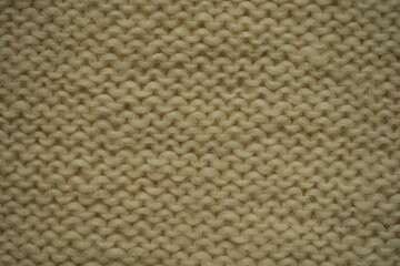 macro texture of white wool knitted fabric. Handcrafted with knitting needles, the soft yarn forms a cozy and natural background. Ideal for textile design, winter themes, handmade crafts, or slow fash