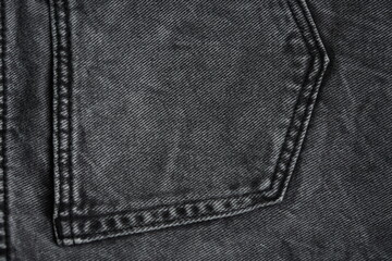texture of black denim jeans with visible pocket lines, seam stitches, and worn or torn fabric...