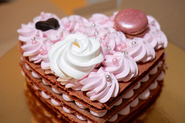 Heart-shaped layered cake with pink frosting and macaron
