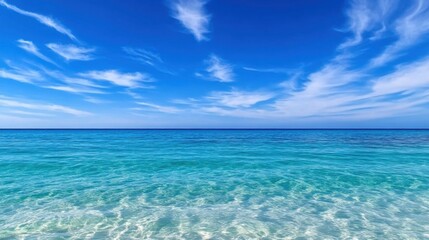 Obraz premium Gentle waves lap at the shore as sunlight sparkles on the clear ocean water. The vast expanse of blue invites relaxation on a warm day, creating a tranquil atmosphere.