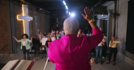 Pastor leading congregation with raised hands in worship, diverse Christian community participating...