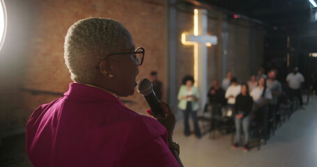 Pastor leading service in church, congregation in spiritual worship with hands raised, focus on...