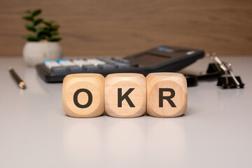 Wooden blocks with the letters OKR on office desk background