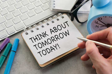 A person is writing on a piece of paper that says Think about tomorrow today