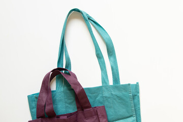 Turquoise and purple eco fabric bag with long handles on white background, eco-friendly alternative
