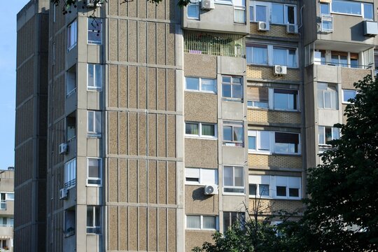 Residential building in brutalist style from the Yugoslav socialist era, featuring concrete panels, small balconies, and air conditioners, typical of Eastern European architecture.