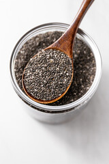 Close-up of chia seeds in a glass jar with a wooden spoon. Healthy superfood concept, ideal for plant-based, vegan, and clean eating themes.