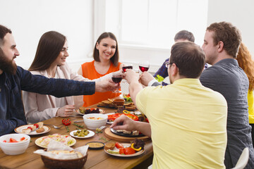 Group of people clink glasses, saying cheers, eat healthy meals at party dinner table in cafe,...