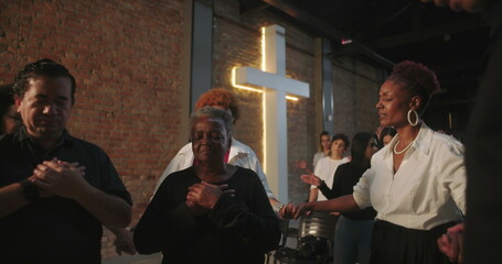Participants holding hands in prayer during church service, spiritual connection, group praying in...