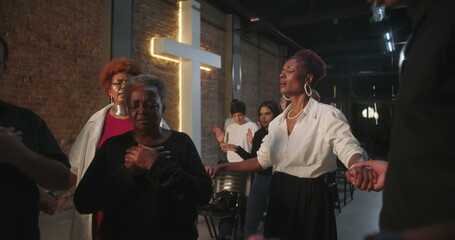 Participants holding hands in prayer during church service, spiritual connection, group praying in...