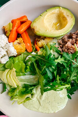 Healthy salad with fresh ingredients and avocado served in a bowl at a lunch setting