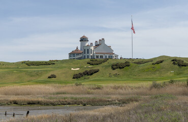 white building on green meadow grass hill next to american flag of the united states of america usa golf course next to hudson river bayonne new jersey