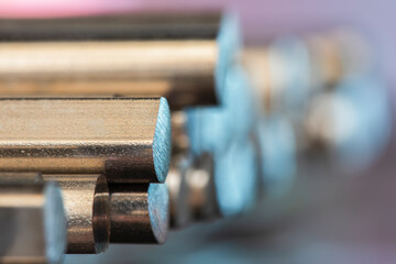 A stack of cut steel bars and non-ferrous metal rods, close-up view with a blurred background