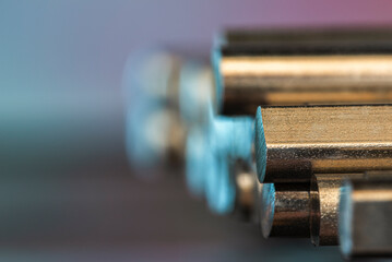 A stack of cut steel bars and non-ferrous metal rods, close-up view with a blurred background