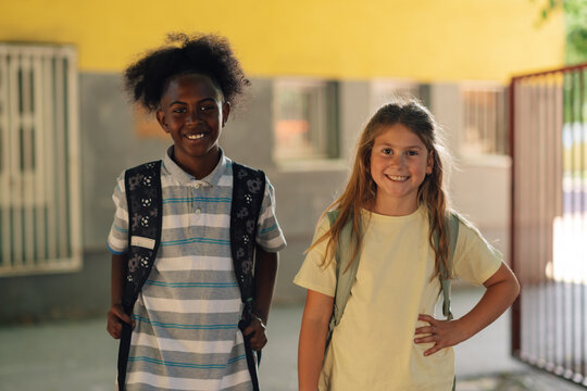 Two smiling students wearing backpacks going back to school - Powered by Adobe