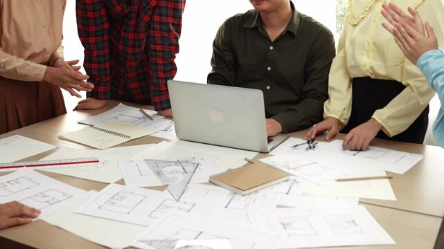 Architect and safety engineer celebrate success design building blueprint project on laptop on table with architectural document and wooden block scatter around at modern office. Closeup. Delineation.