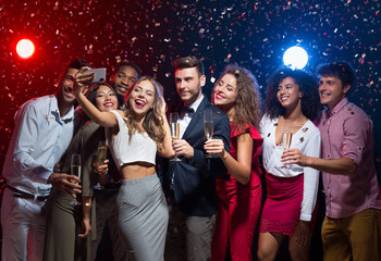 Holiday group selfie. Young friends having fun at New Year's Eve party and taking photo, copy space