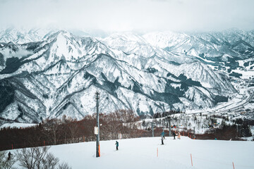Obraz premium A breathtaking panoramic view of snow-covered mountain ranges including Ishiuchi Maruyama, Yuzawa Kogen, and distant peaks near Echigo-Yuzawa in Niigata, Japan, captured from Gala Yuzawa station.