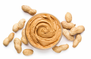 Bowl of peanut butter and unshelled scattered peanuts on white background, isolated
