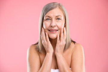 Smiling woman with healthy skin on pink background