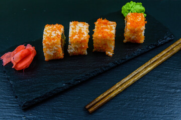 Sushi roll philadelphia with salmon, rice, cheese, cucumber, avocado and caviar on a slate board. Japanese food