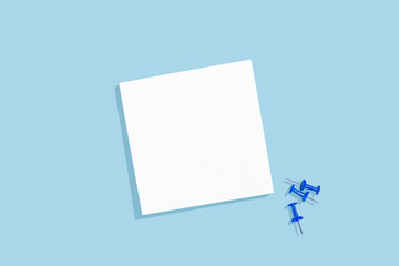 Empty white paper sheet for notices with blue stationery pins on a blue background