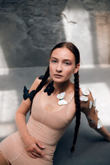 Portrait of a model sitting gracefully with butterflies in a serene indoor setting during soft natural light