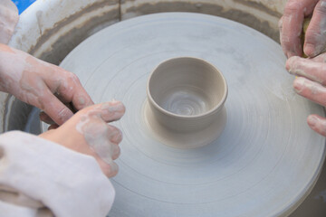master class with children on clay modeling on a potter's wheel. hands close-up. teaching children pottery