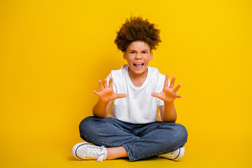 Cheerful young boy gesturing joyfully against vibrant yellow background, expressing emotion and...