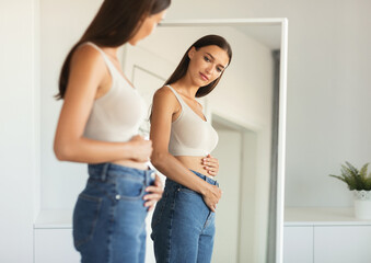 Young Woman Touching Flat Belly Expecting Baby And Enjoying First Months Of Pregnancy Posing...