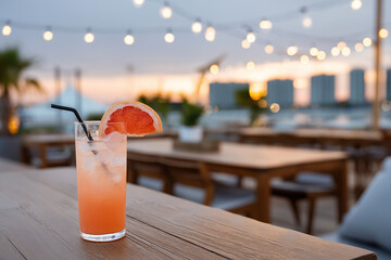 Beautiful cocktail served at an outdoor bar with hanging lights at sunset