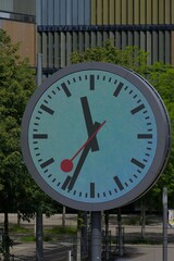Iconic round clock face, vibrant purple hues, and classic black hands against lush greenery. A symbol of precision and timeless design in an urban setting.