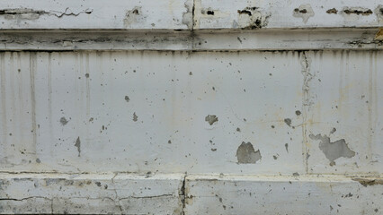 Peeling paint on the wall, peeling white paint on the fence wall, old concrete wall has cracks and peeling paint, white painted brick wall surface has scratches and peeling paint.