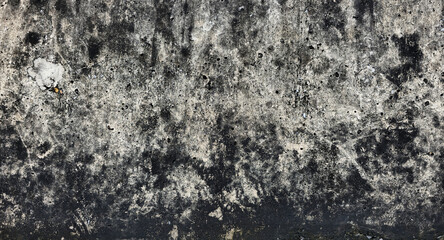 The old gray cement wall is stained, peeled, and has a peeling surface. The wall has been stained with black stains over time. Walls of ancient buildings. Texture and background image.