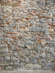 Close-up of a textured wall combining red brick and grey stone masonry.