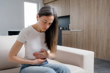 Woman experiences discomfort from chronic illness in her living room space